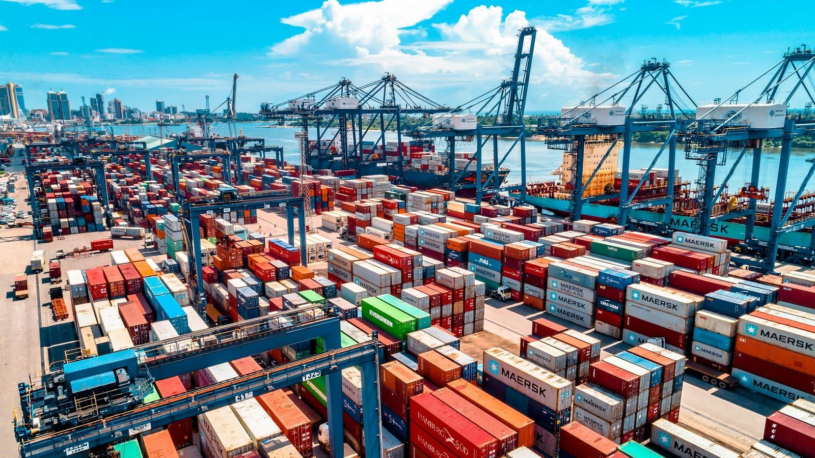 무역 항구에 쌓인 컨테이너와 하역 장비가 보이는 장면